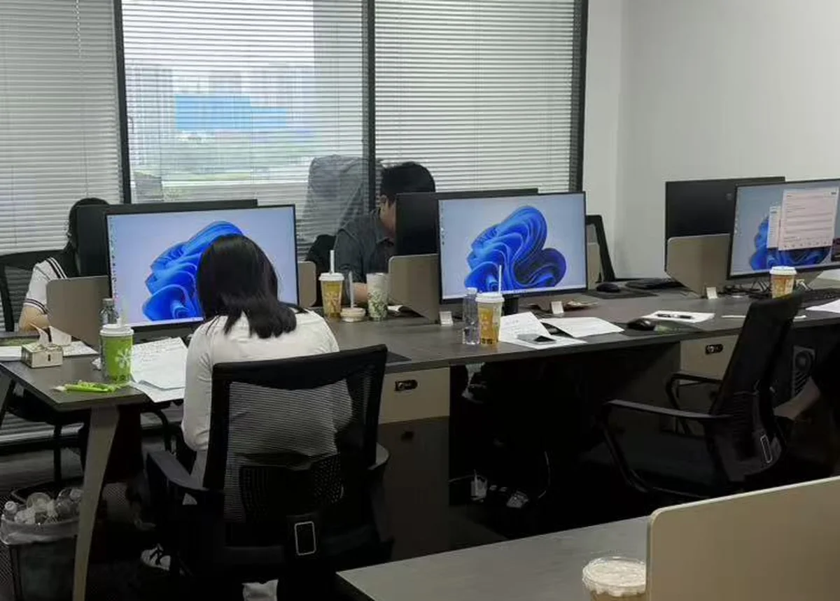 Team members working at their own systems along a shared desk row.